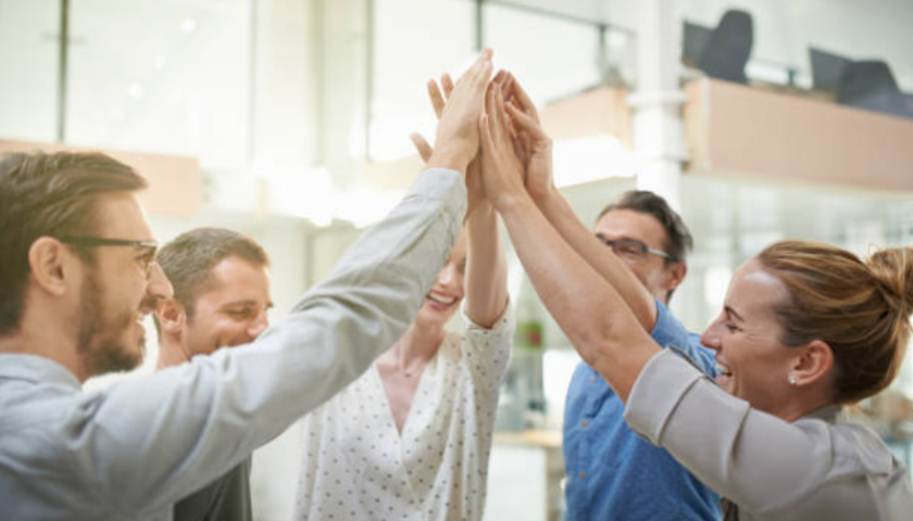Co-workers sharing a group high-five in an office setting