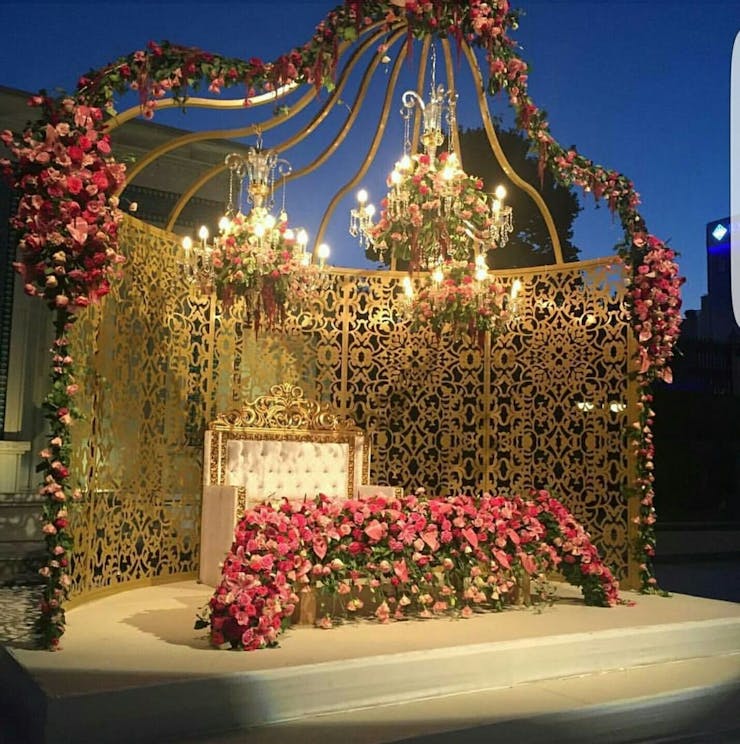 floral chandelier and golden structured wall for engagement stage decoration.
